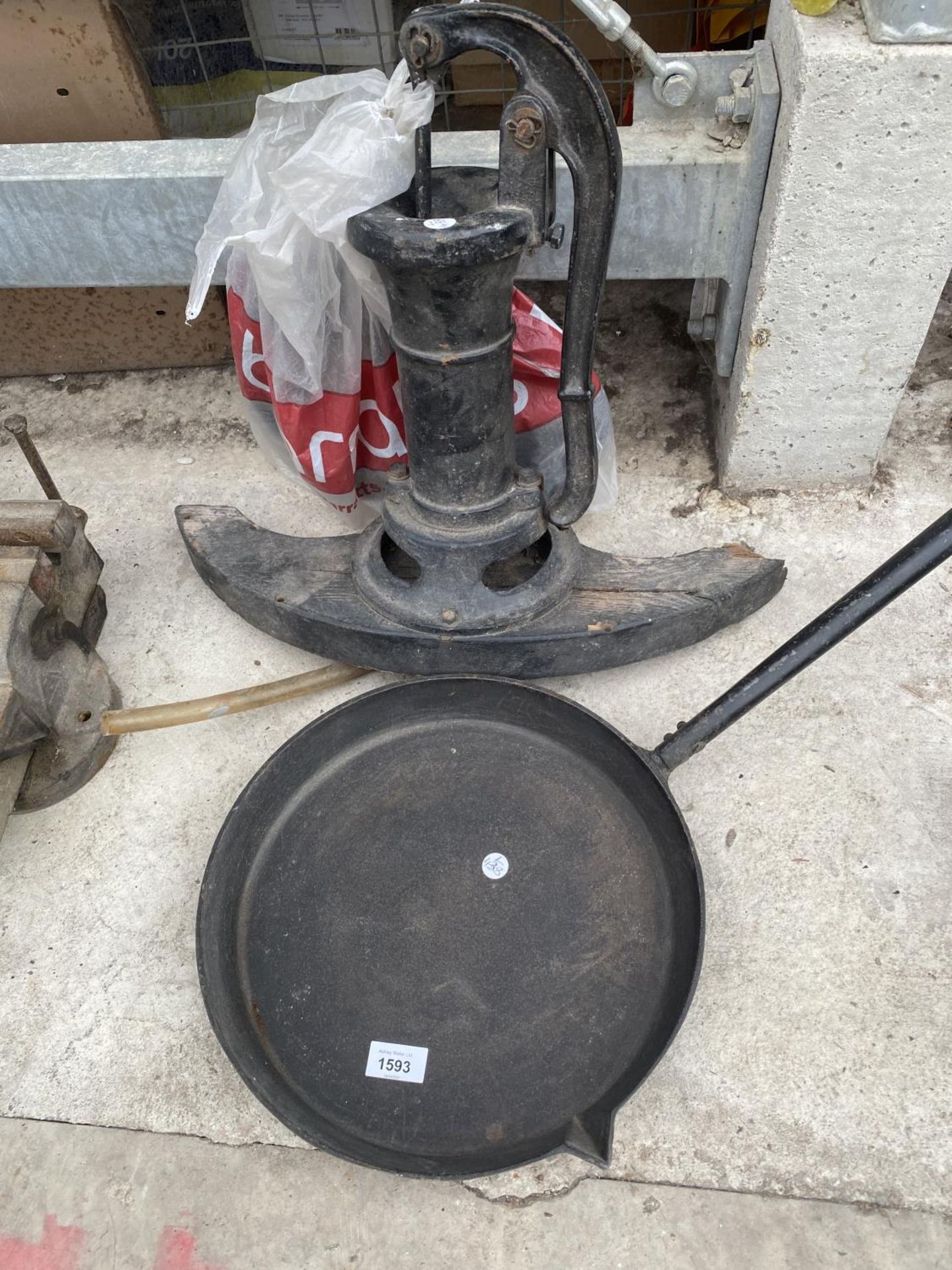 A LARGE CAST IRON PAN AND A FURTHER CAST IRON WATER PUMP