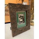 A CARVED WOODEN TABLE PICTURE FRAME WITH SILVER DETAIL 21.5CM X 26.5CM