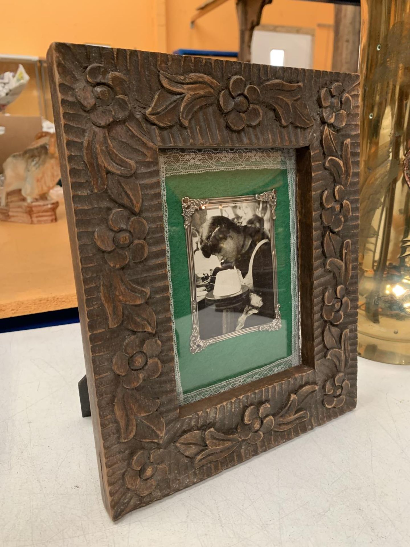 A CARVED WOODEN TABLE PICTURE FRAME WITH SILVER DETAIL 21.5CM X 26.5CM