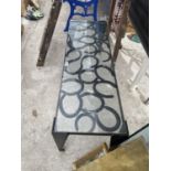 A METAL COFFEE TABLE WITH HORSE SHOE AND GLASS TOP