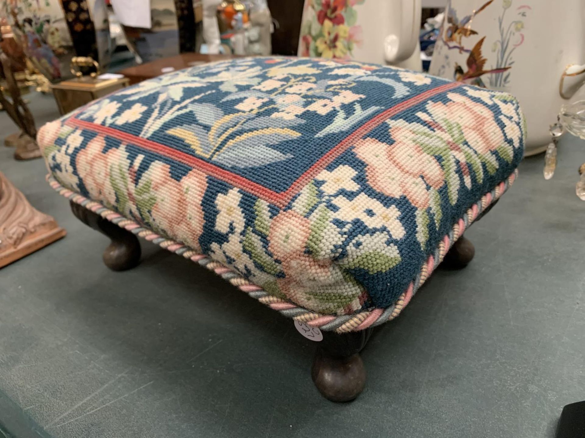 A SMALL VINTAGE FOOTSTOOL WITH MAHOGANY LEGS AND A TAPESTRY TOP 37CM X 25CM X 15CM