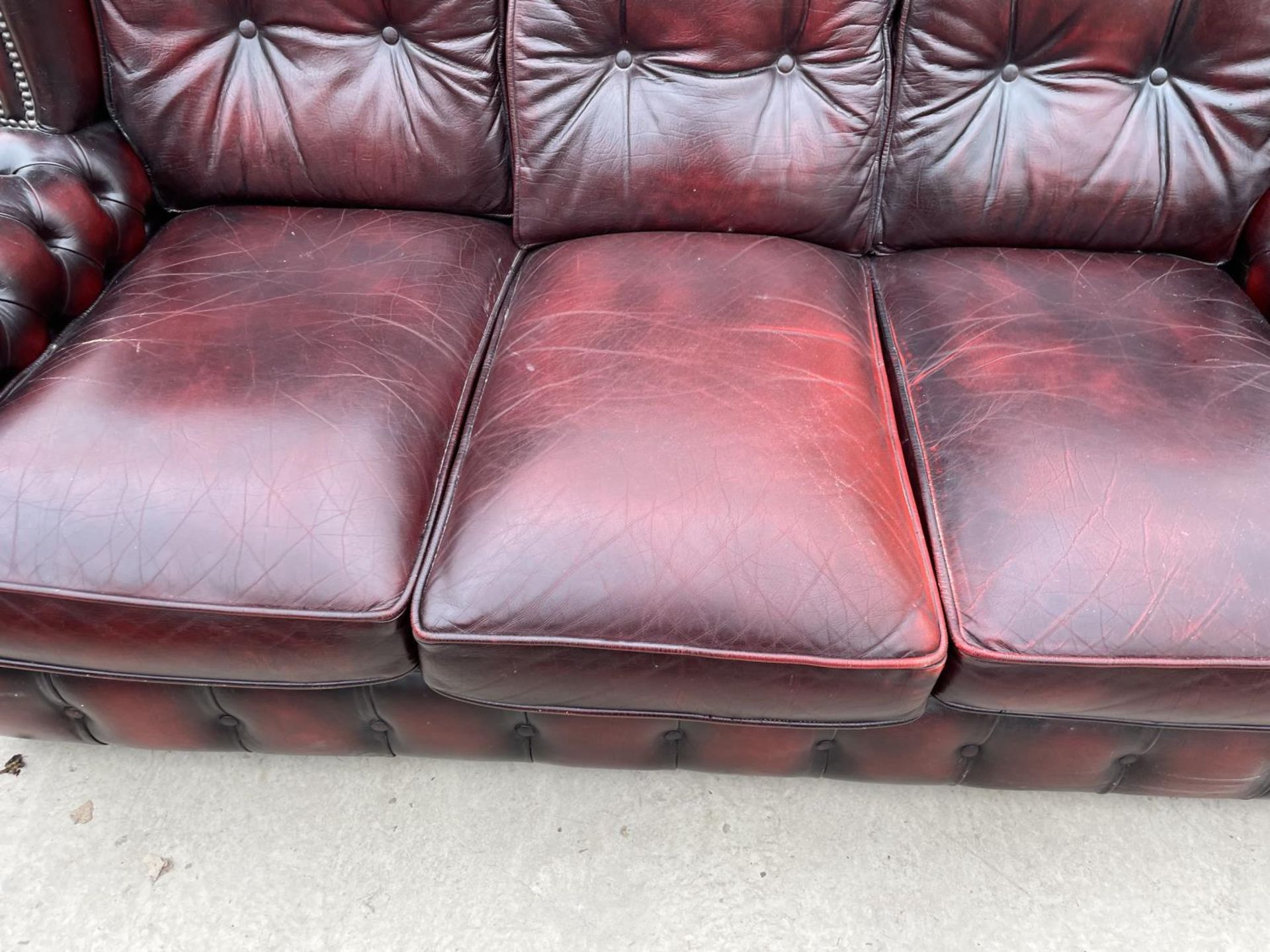 AN OXBLOOD LEATHER THREE SEATER SOFA WITH BUTTONED BACK AND ARMS - Image 4 of 6