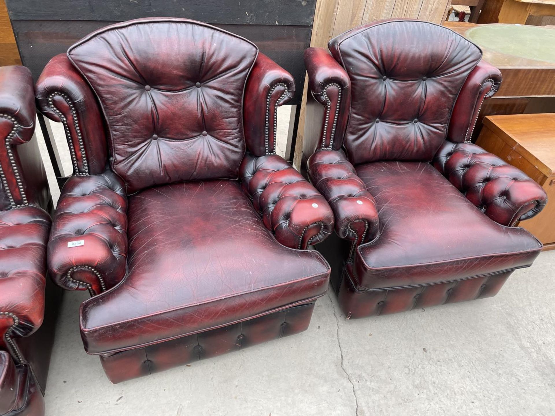 TWO OXBLOOD LEATHER ARMCHAIRS WITH BUTTONED BACK AND ARMS