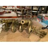 TWO LARGE BRASS CANNONS AND TWO CANDELABRAS PLUS A DECORATIVE HANGING DOOR KNOCKER