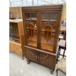 AN EARLY 20TH CENTURY OAK TWO DOOR DISPLAY CABINET WITH AMBER PANELS AND CUPBOARDS TO THE BASE,