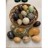 A LARGE ASSORTMENT OF ONYX AND STONE EGGS IN A BASKET