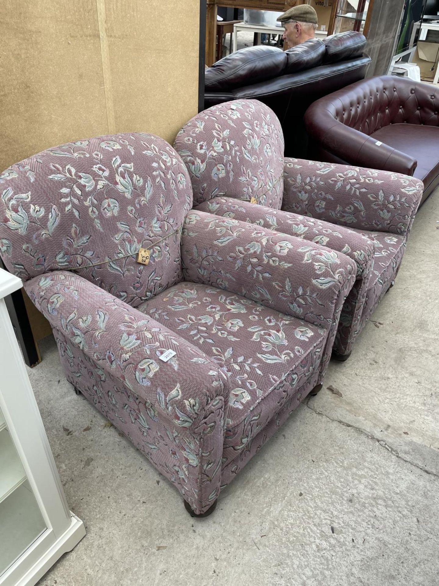 A PAIR OF EDARDIAN SPRUNG AND UPHOLSTERED EASY CHAIRS ON FRONT BUN FEET