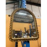 AN ARCHED MIRROR IN A DECORATIVE GILT FRAME