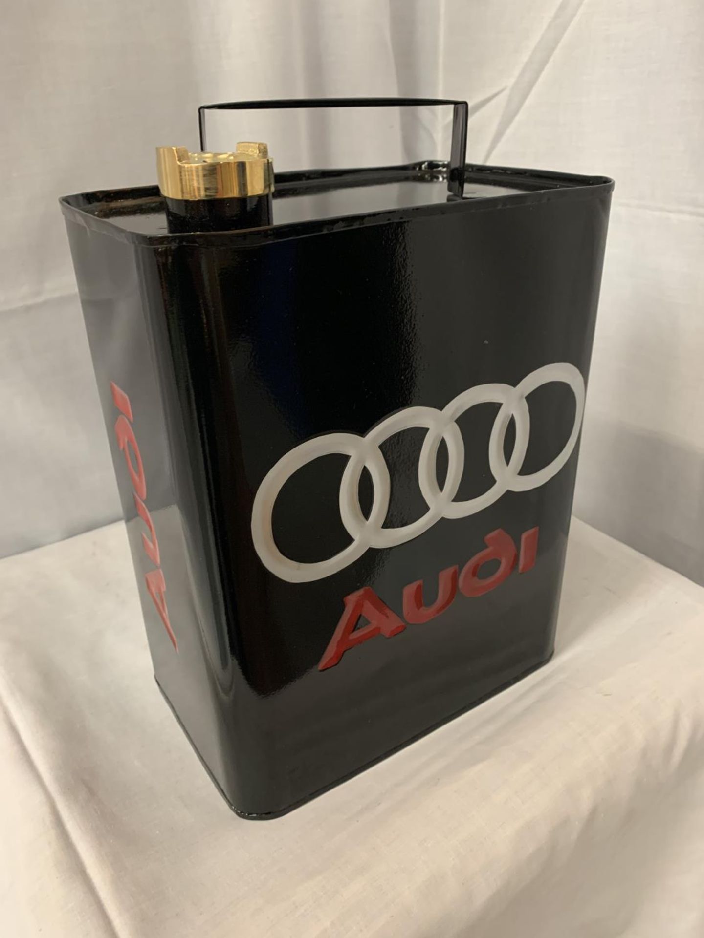 A BLACK METAL 'AUDI' FUEL CAN WITH A BRASS LID