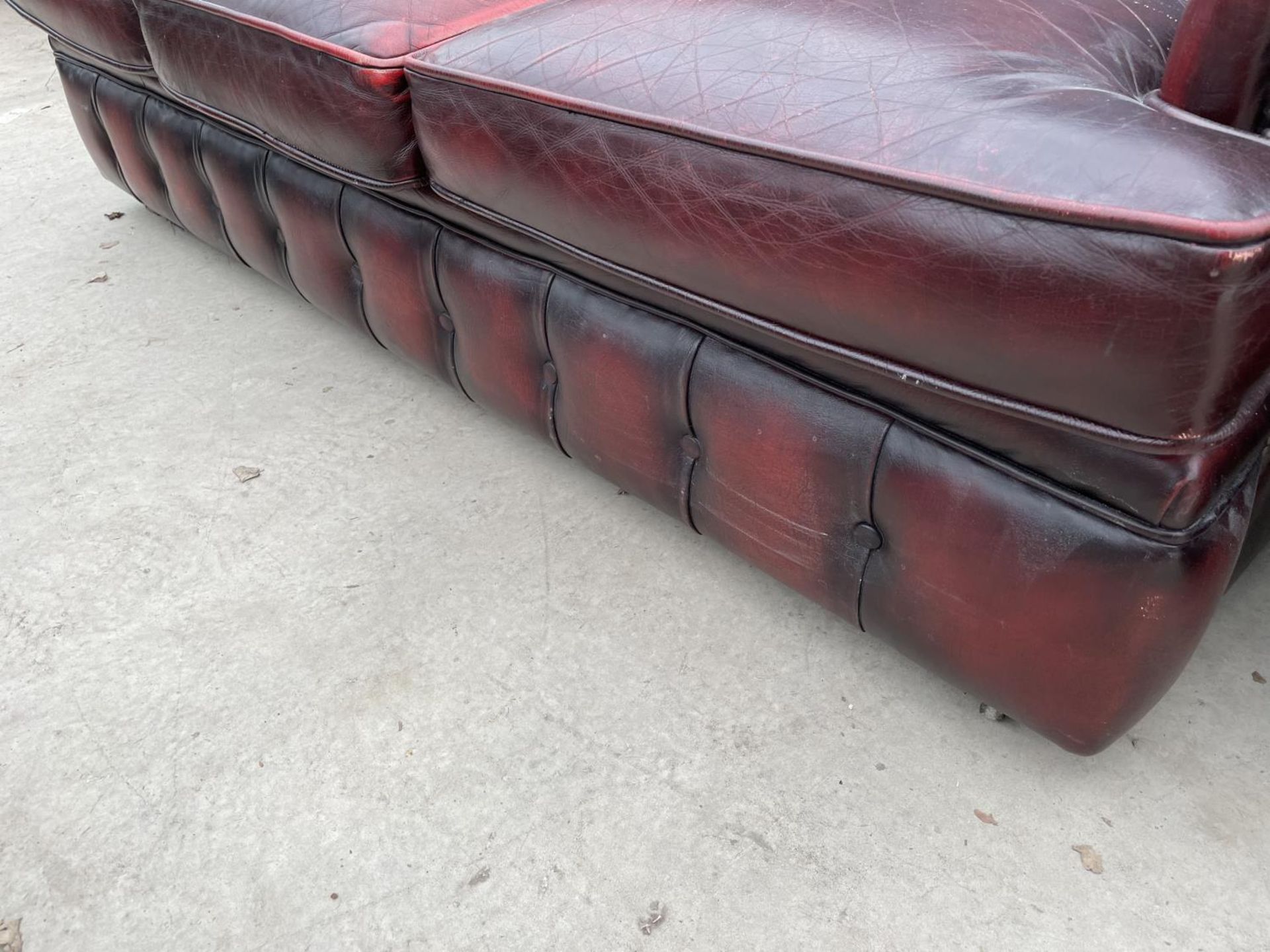 AN OXBLOOD LEATHER THREE SEATER SOFA WITH BUTTONED BACK AND ARMS - Image 5 of 6