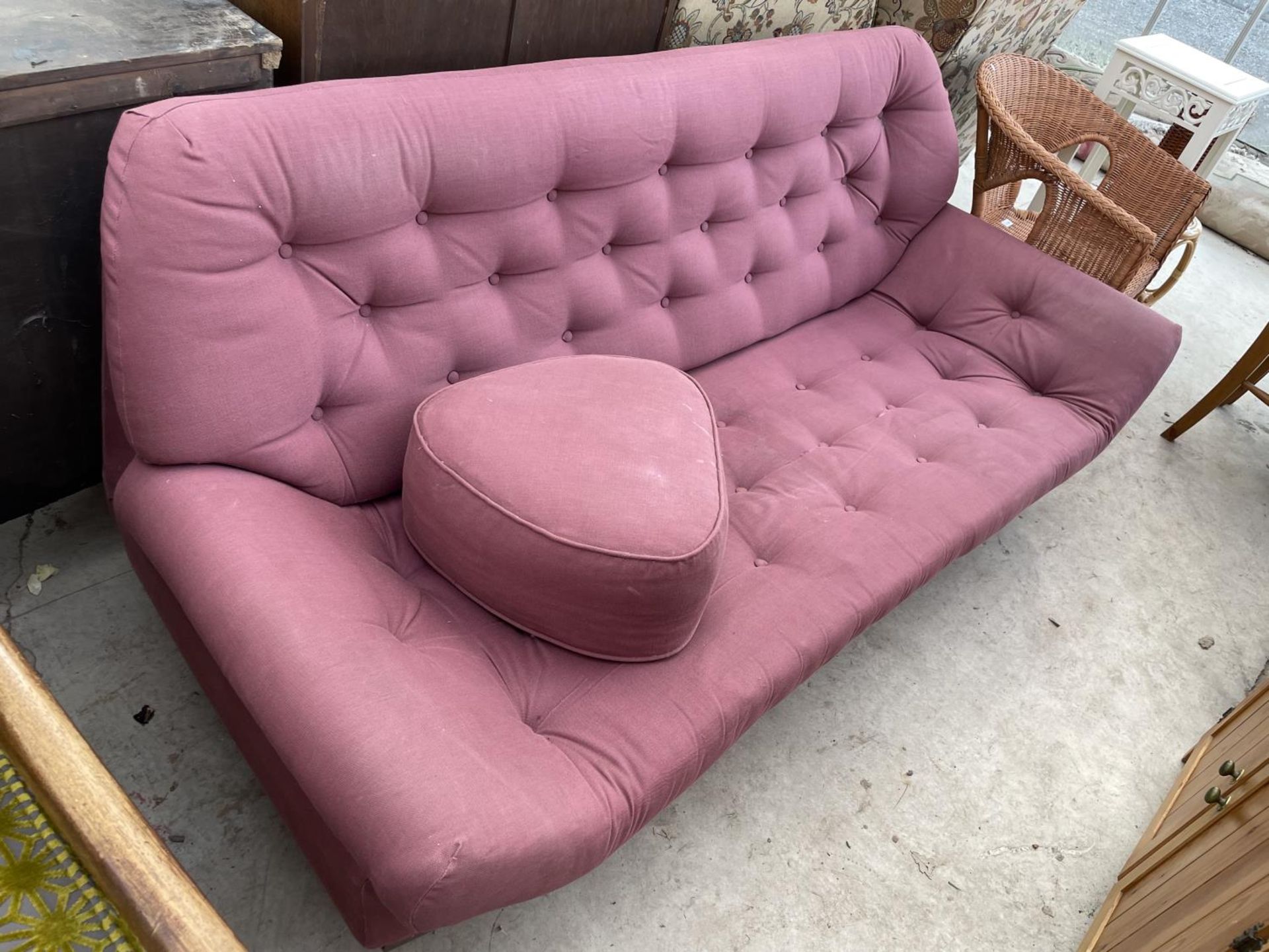 A 1970'S STYLE BUTTON BACK SETTEE WITH LOW RAKING ARMS AND MATCHING POUFFE