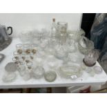 A LARGE ASSORTMENT OF GLASS WARE TO INCLUDE DECANTOR, BOWLS AND TUMBLERS ETC