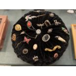 A CIRCULAR DECORATIVE CUSHION WITH AN ASSORTMENT OF BROOCHES ATTACHED