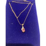 A 9 CARAT GOLD PENDANT WITH A PINK STONE AND FURTHER CLEAR STONES