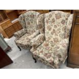 A PAIR OF MODERN WING BACK FIRESIDE CHAIRS ON FRONT CABRIOLE LEGS, HAVING DISTINCT FLORAL DECORATION