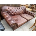 A VICTORIAN STYLE LEATHER CHESTERFIELD SETTEE WITH DEEP SEATING AND RAKING ARMS, ON TURNED LEGS,