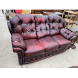 AN OXBLOOD BUTTON-BACK THREE SEATER SETTEE