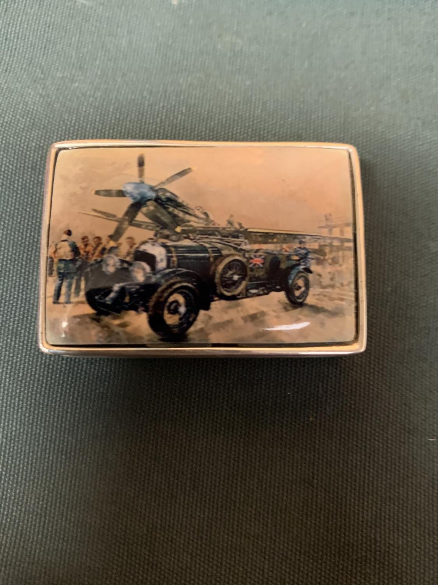 A LARGE RECTANGULAR MARKED 925 SILVER PILL BOX WITH AN ENAMEL TOP DEPICTING A BENTLEY AND A SPITFIRE