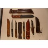 A COLLECTION OF FIVE SURVIVAL KNIVES, ONE INCLUDES A WINE BOTTLE OPENER. ANOTHER MILITARY EXAMPLE
