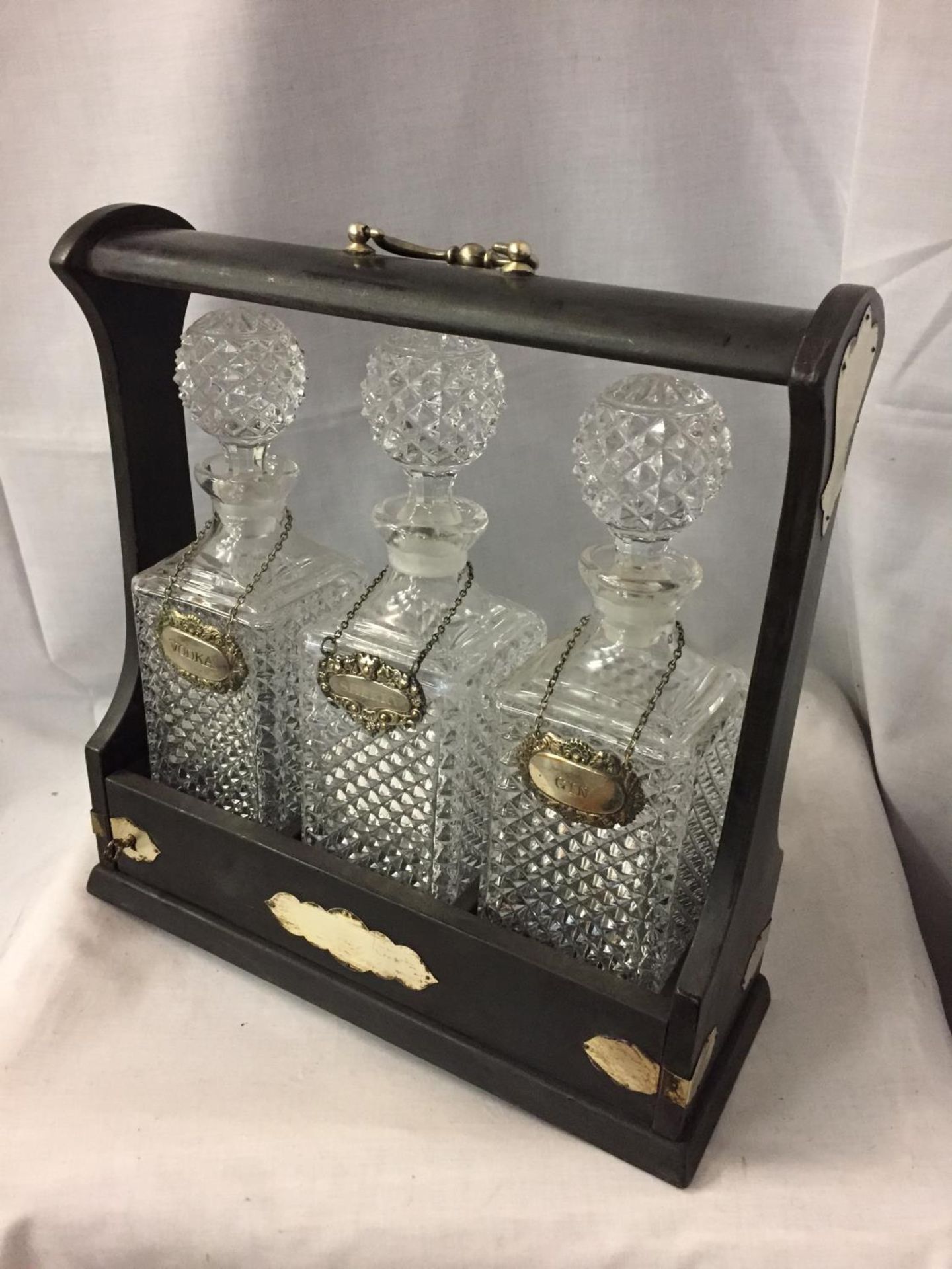 A DECORATIVE TANTALUS WITH THREE GLASS DECANTERS AND THREE SILVER PLATED DRINK LABELS