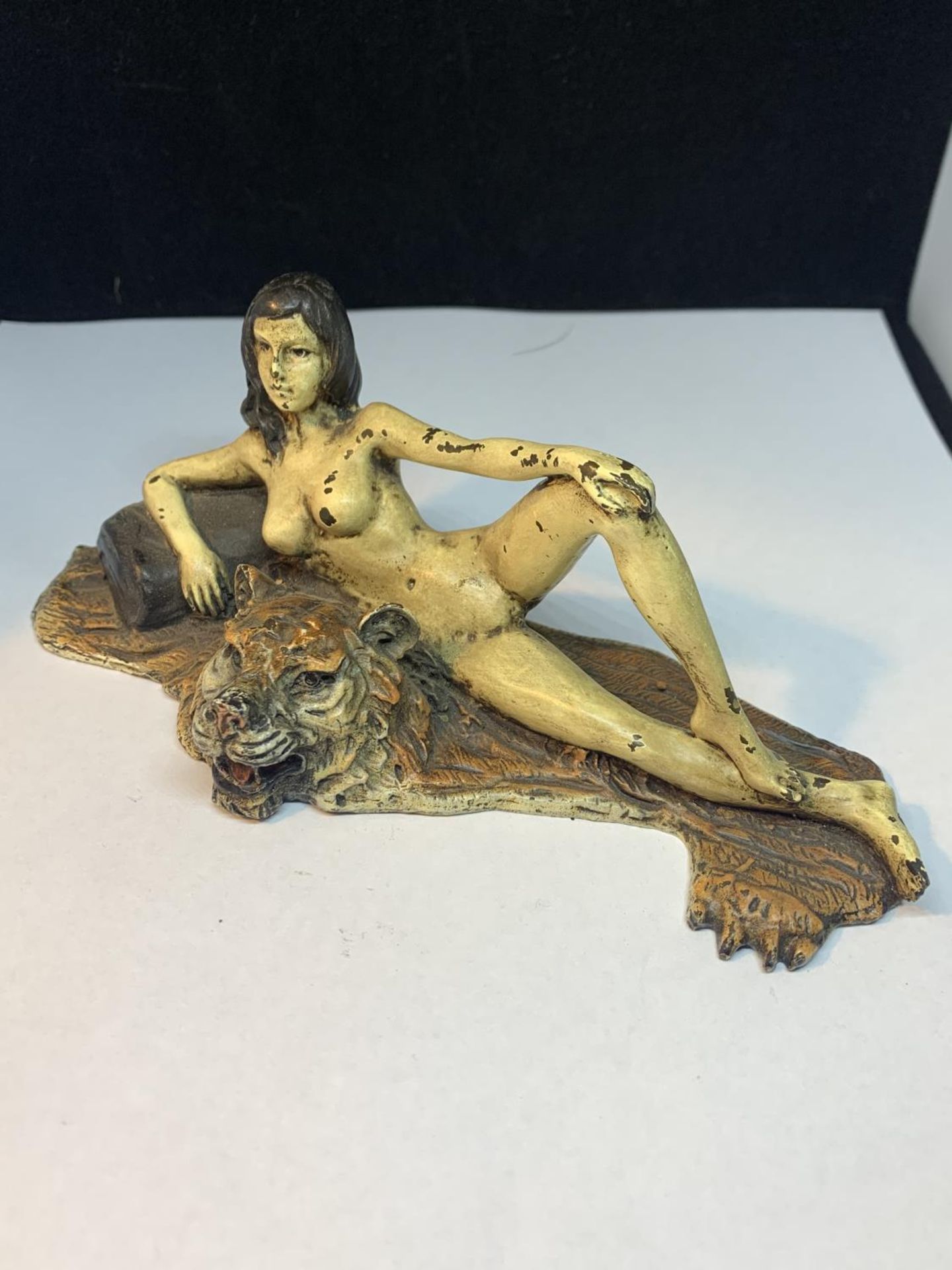 A COLD PAINTED BRONZE FIGURINE OF A NUDE LADY LYING ON A TIGER RUG