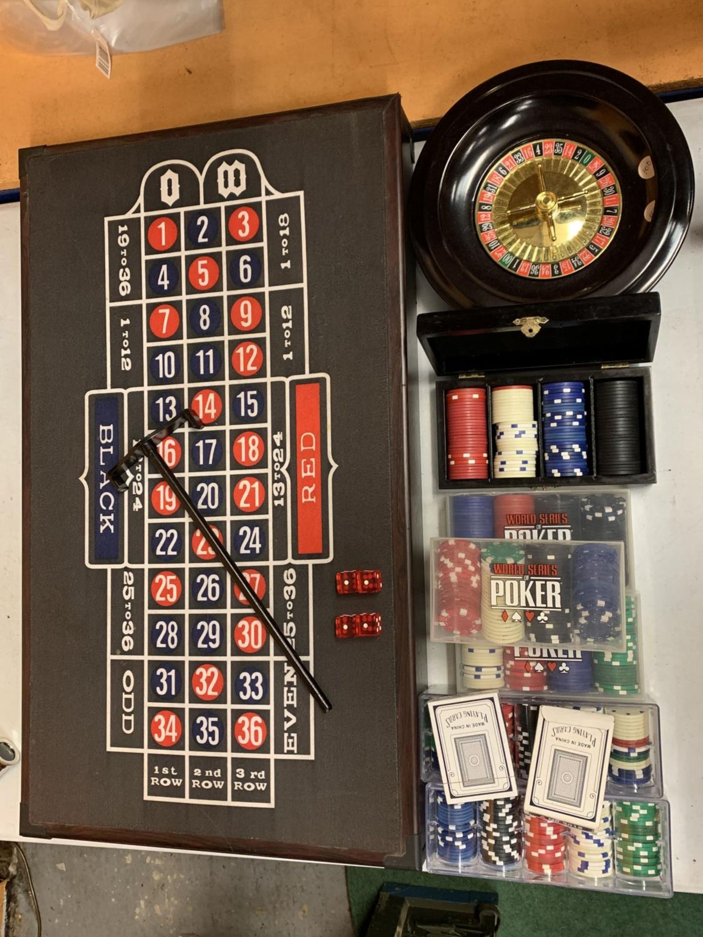A ROULETTE BOARD WITH WHEEL, CHIPS, DICE ETC