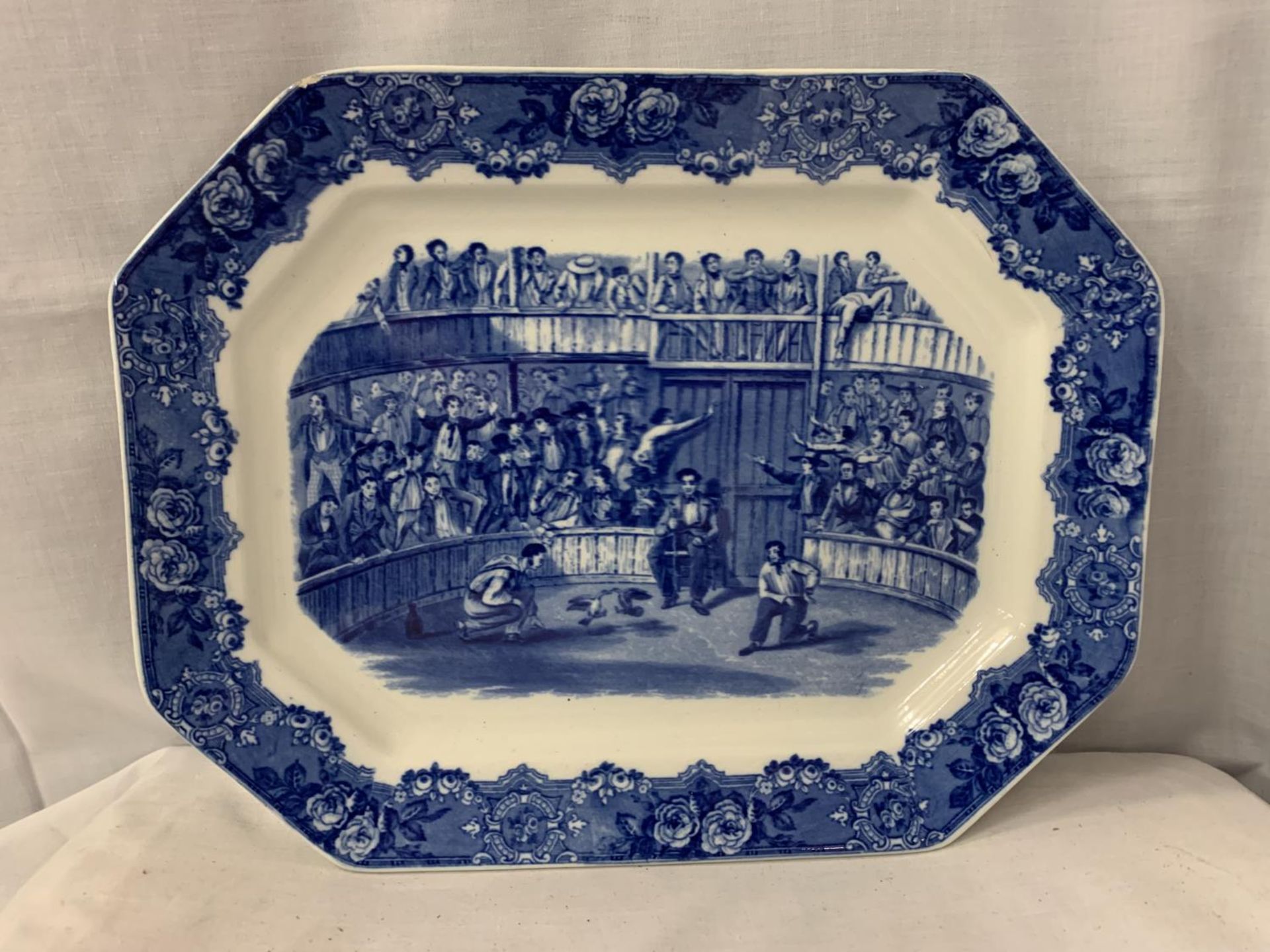 A LARGE BLUE AND WHITE MEAT PLATTER DEPICTING COCK FIGHTING AND STAMPED SPANISH FESTIVITIES 1798