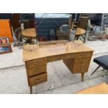 A RETRO TEAK INVERTED BOWFRONTED DRESSING TABLE ENCLOSING SEVEN DRAWERS, 46" WIDE, WITH TRIPLE