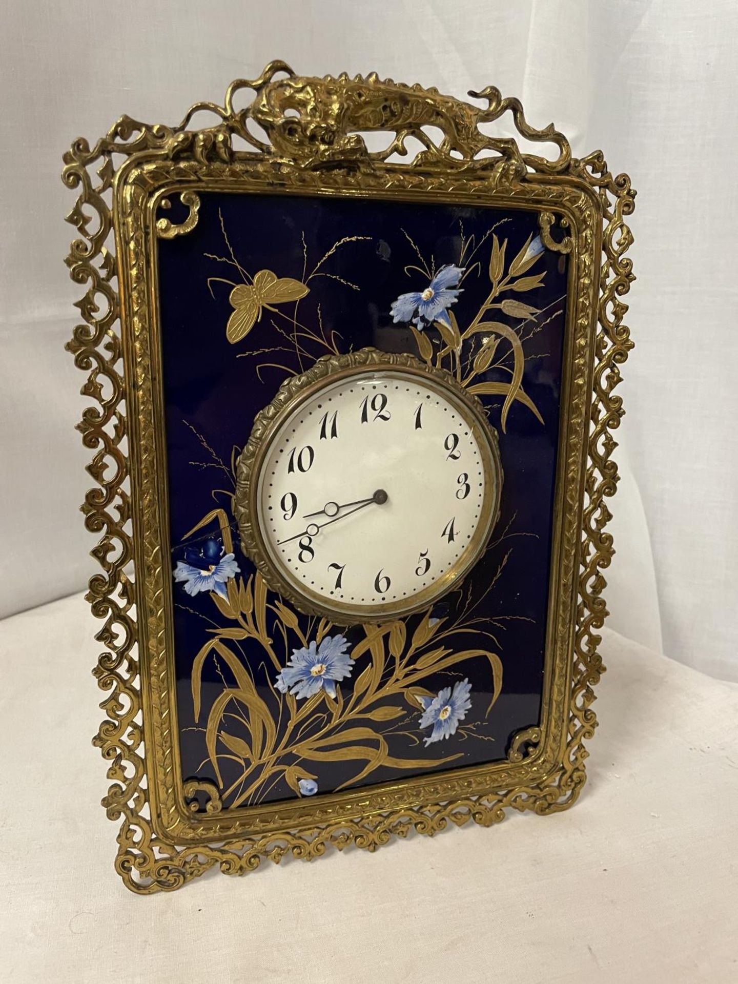 A BRASS AND CERAMIC EASEL STYLE MANTLE CLOCK WITH HAND PAINTED FLOWERS 30CM X 21CM (A/F)