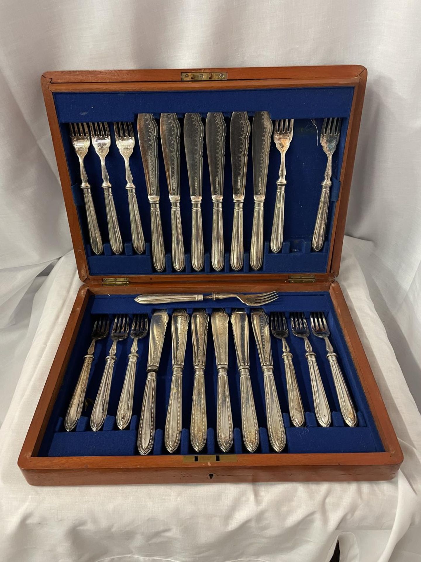 A WOODEN BOX CONTAINING TWELVE SILVER PLATED FISH KNIVES AND FORKS