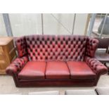 AN OXBLOOD THREE SEATER BUTTON-BACK WINGED SETTEE