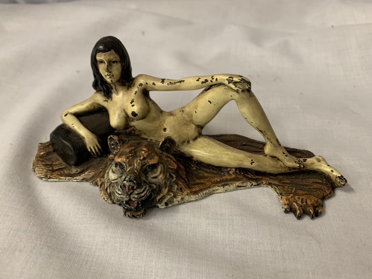 A COLD PAINTED BRONZE FIGURINE OF A NUDE LADY LYING ON A TIGER RUG