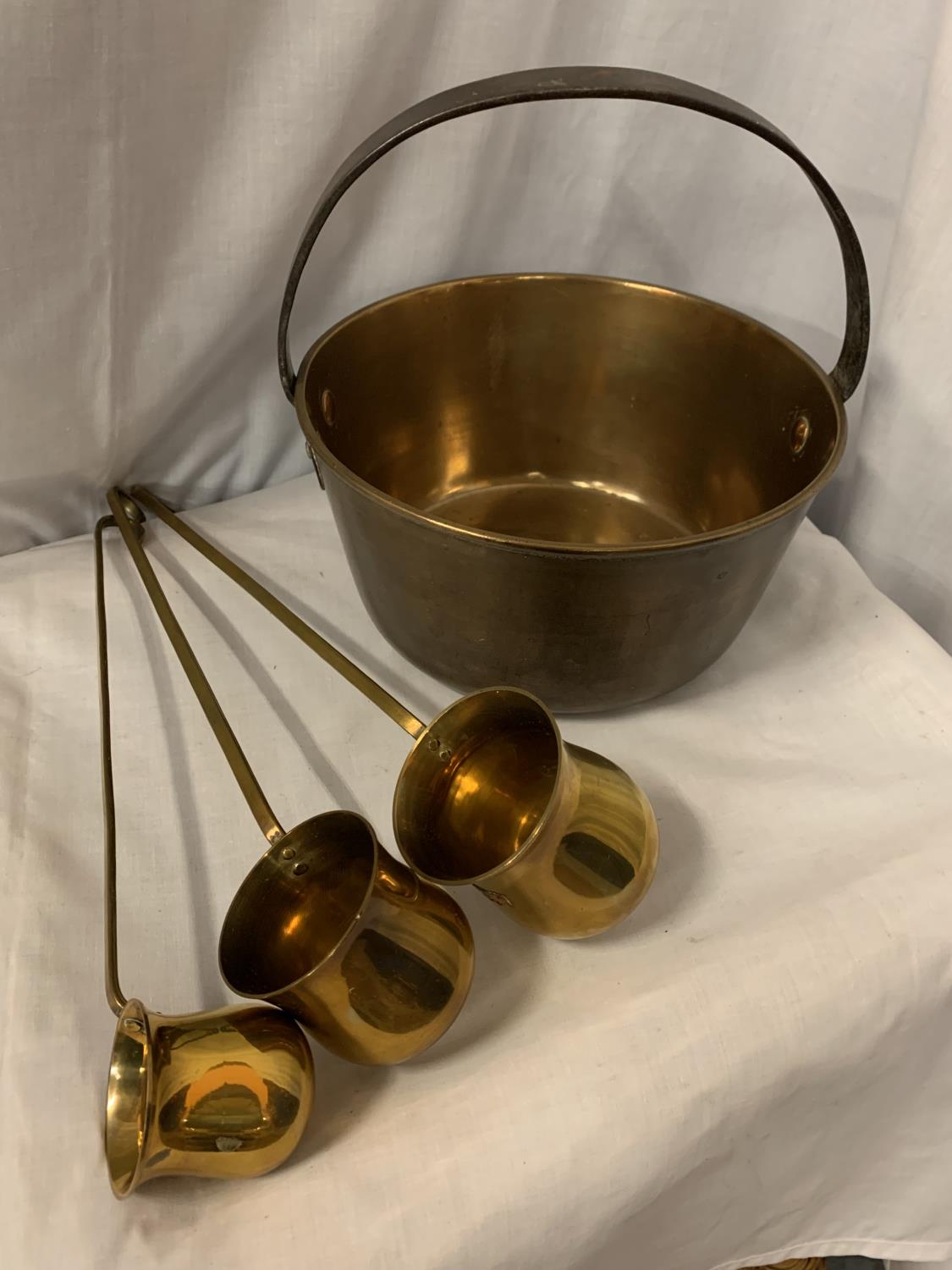 A BRASS JAM PAN AND THREE BRASS LADLES