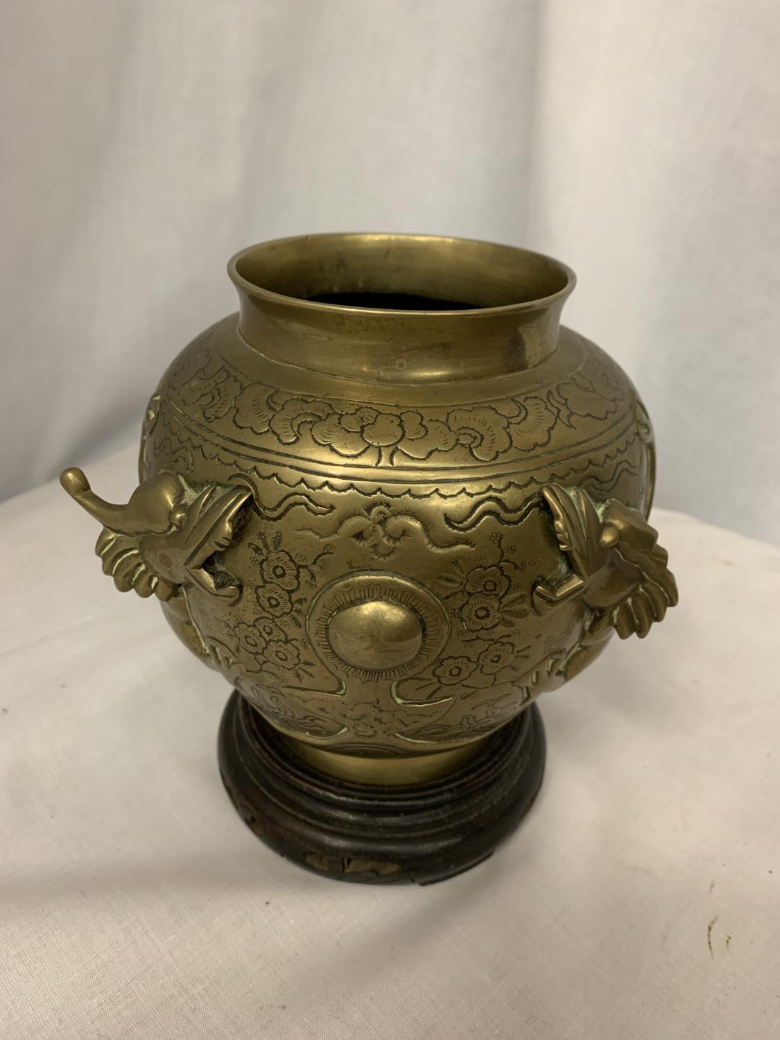 A CHINESE BRASS POT MANJI SYMBOL WITH DRAGONS ON A WOODEN STAND