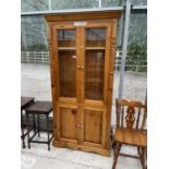A MODERN PINE TWO DOOR GLAZED CABINET WITH CUPBOARDS TO THE BASE, 38.5" WIDE