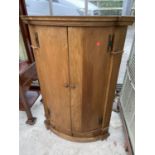 A GEORGE III STYLE OAK TWO DOOR BOWFRONTED CORNER CUPBOARD WITH SHAPED INTERIOR SHELVES AND THREE