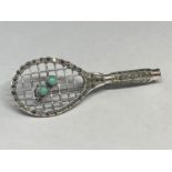 A MARKED SILVER BROOCH WITH TWO GREEN STONES DEPICTING A TENNIS RACKET AND BALLS
