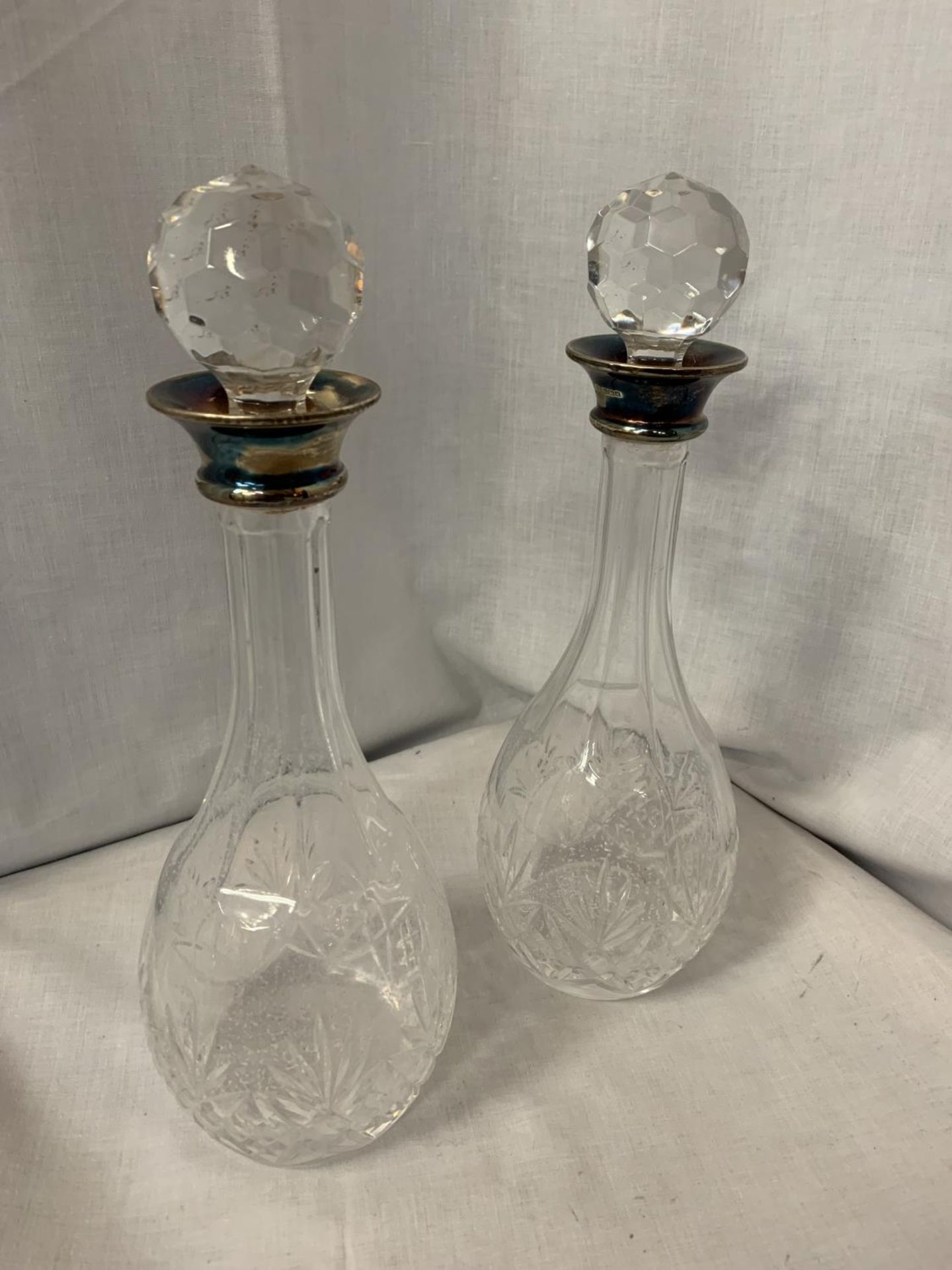 TWO MATCHING GLASS DECANTERS WITH HALLMARKED SILVER COLLARS AND GLASS STOPPERS