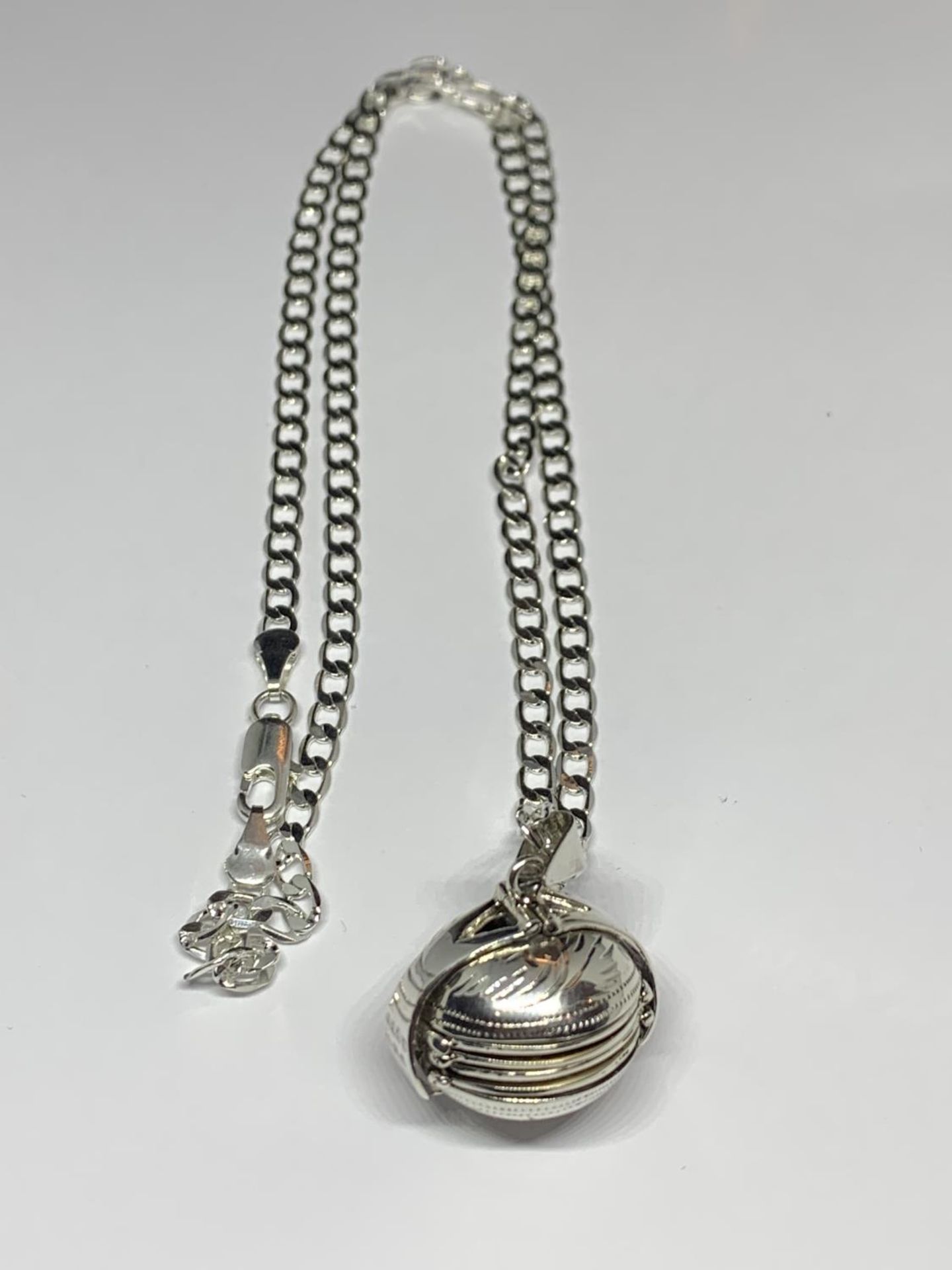 A MARKD SILVER NECKLACE WITH AN ORNATE BALL LOCKET PENDANT
