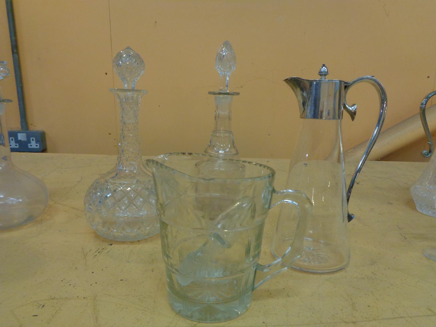 A GLASS CLARET JUG WITH SILVER PLATE COLLAR, TWO CUT GLASS DECANTERS AND AN ETCHED MID CENTURY WATER