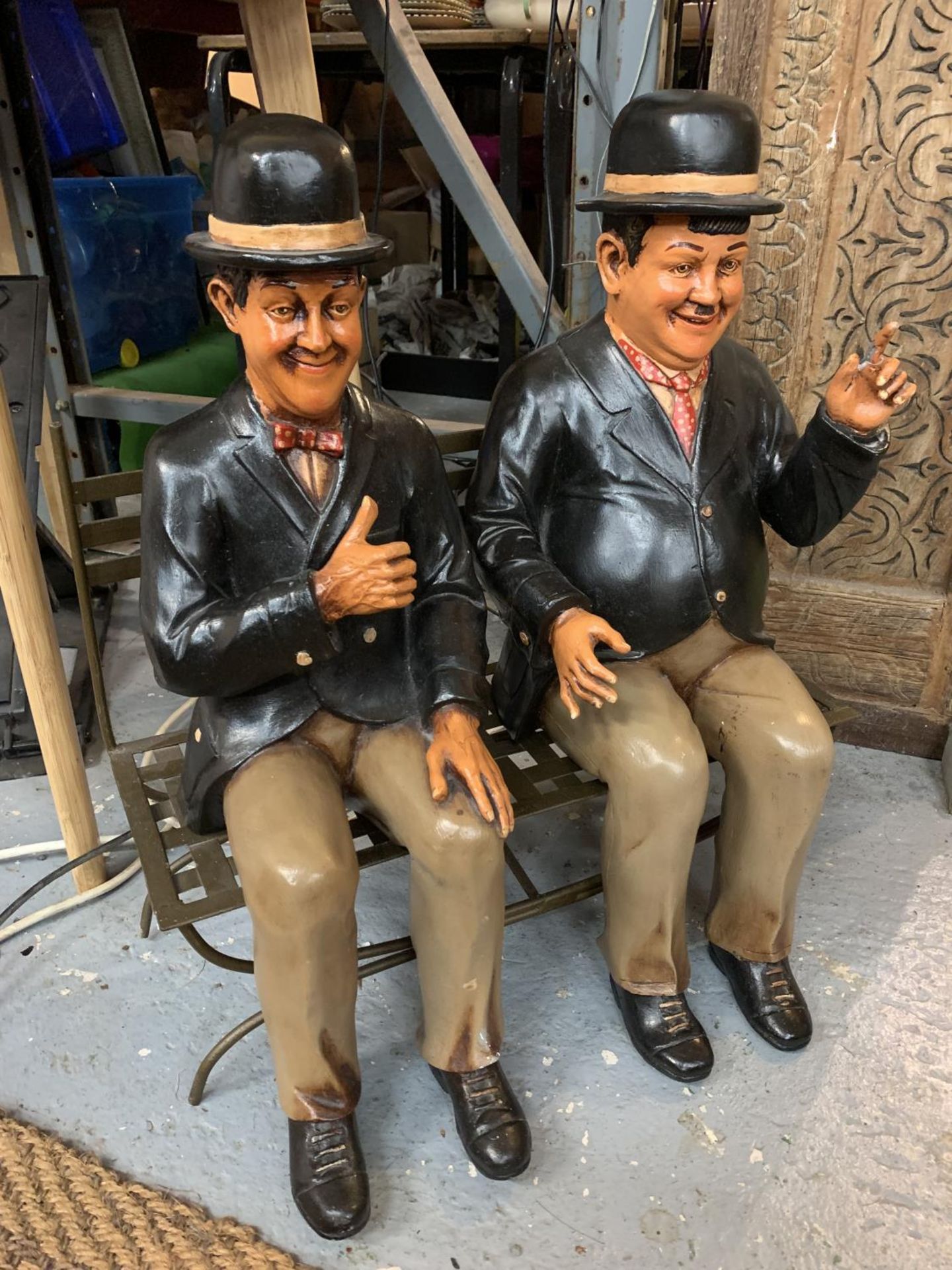 LARGE MODELS OF LAUREL AND HARDY SAT ON A CAST METAL SEAT
