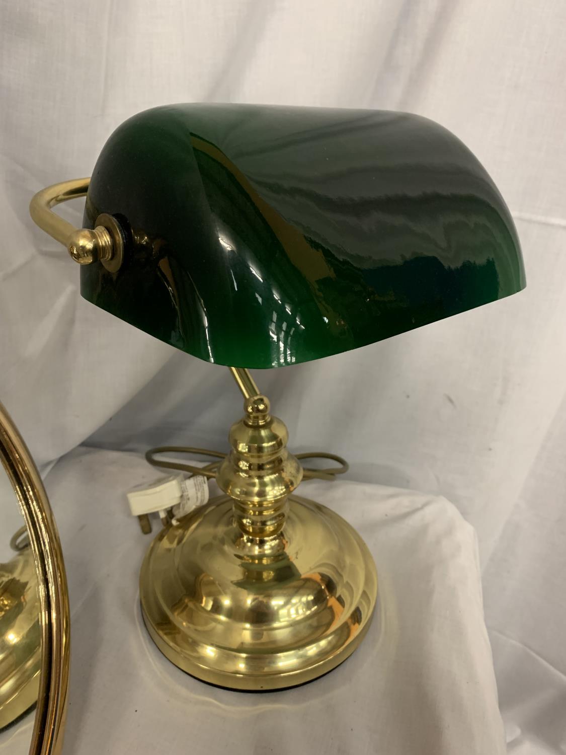 A BRASS FRAMED MIRROR AND A BRASS DESK LAMP WITH A GREEN GLASS SHADE