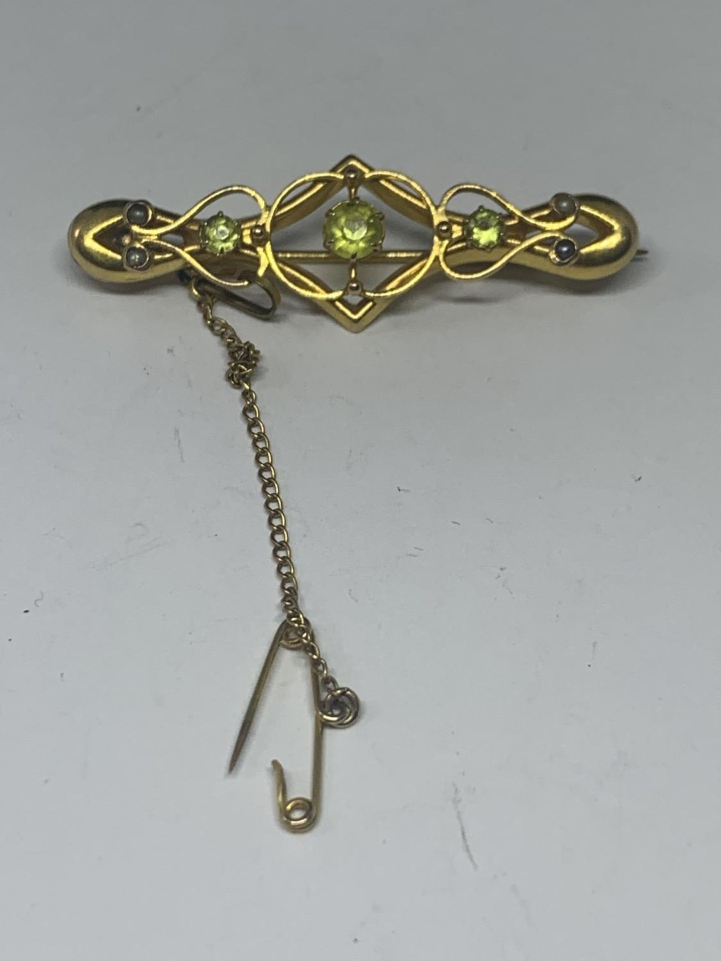 A 9 CARAT GOLD VICTORIAN BROOCH WITH PALE GREEN STONES AND A SAFETY CHAIN GROSS WEIGHT 2.97 GRAMS