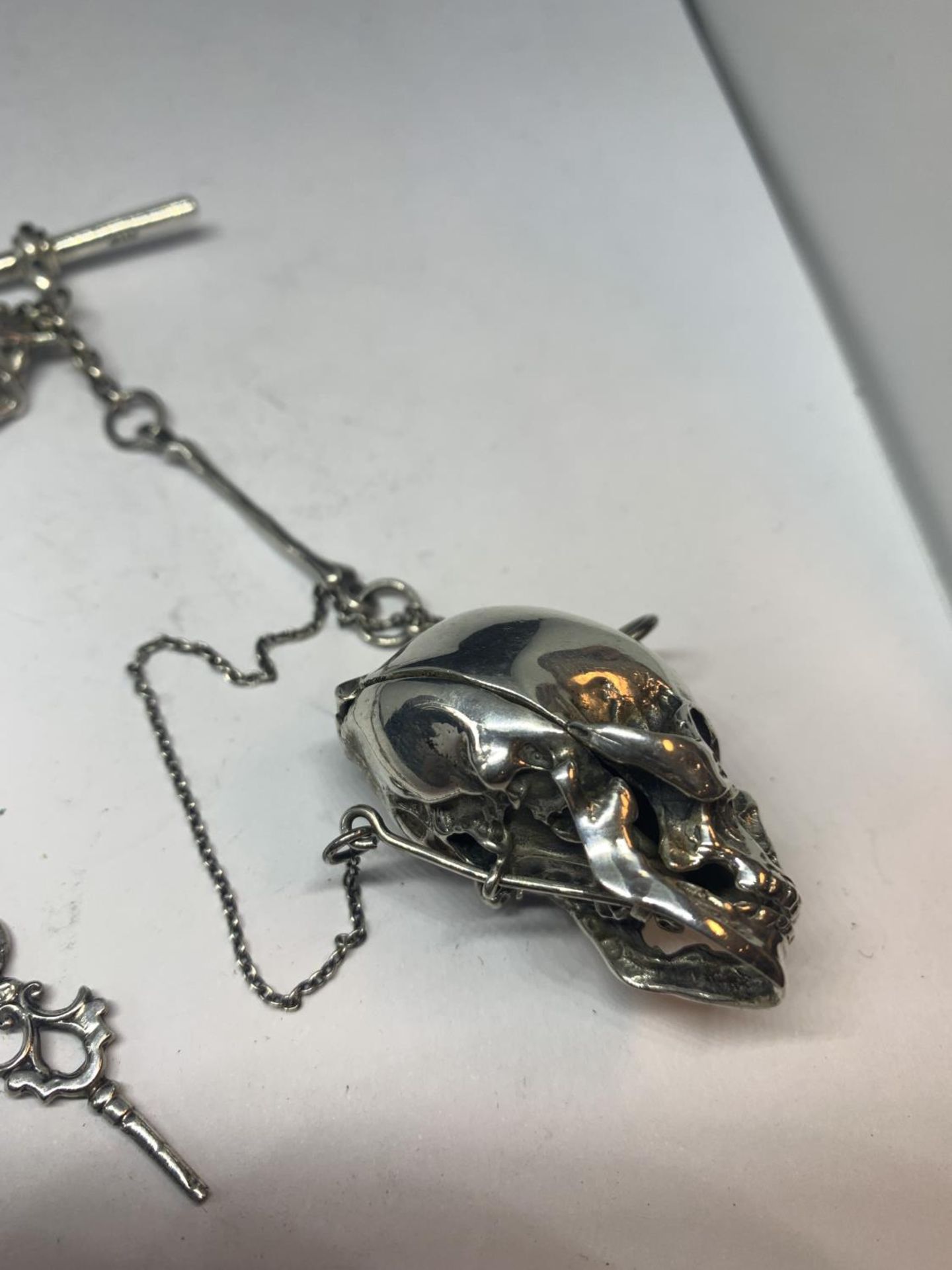 A HEAVY SILVER ALBERT CHAIN WITH LARGE SKULL FOB AND BONE, HAND ETC DESIGN - Image 5 of 10