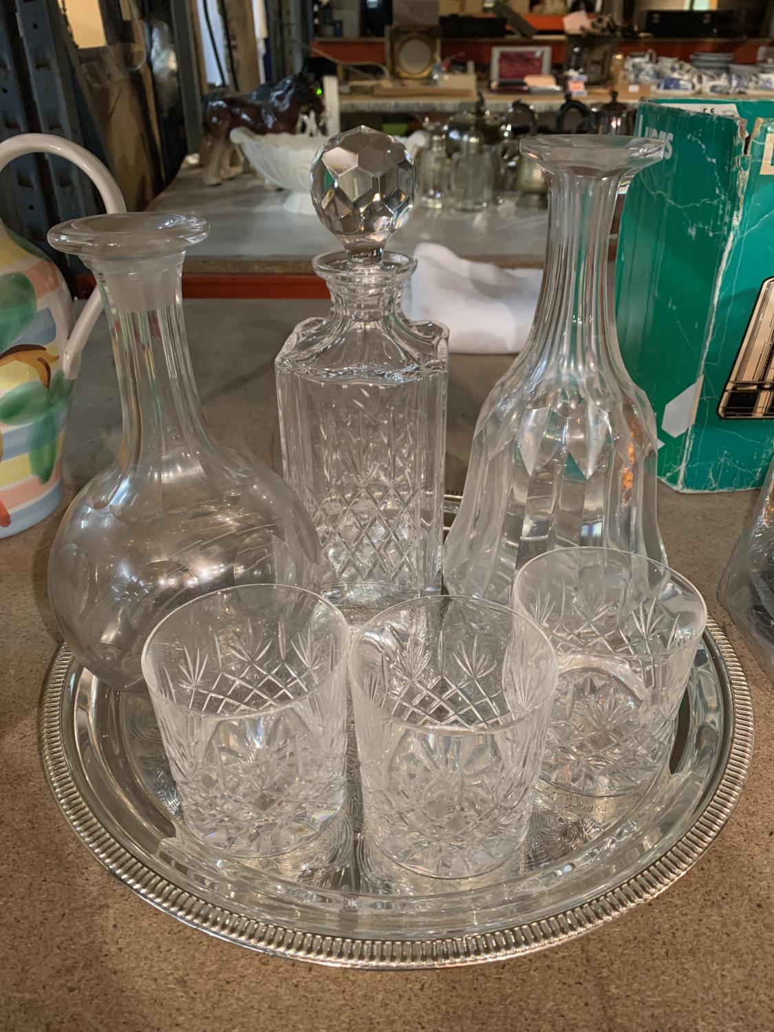 A PLATED TRAY WITH THREE DECANTERS AND THREE CUT GLASS TUMBLERS