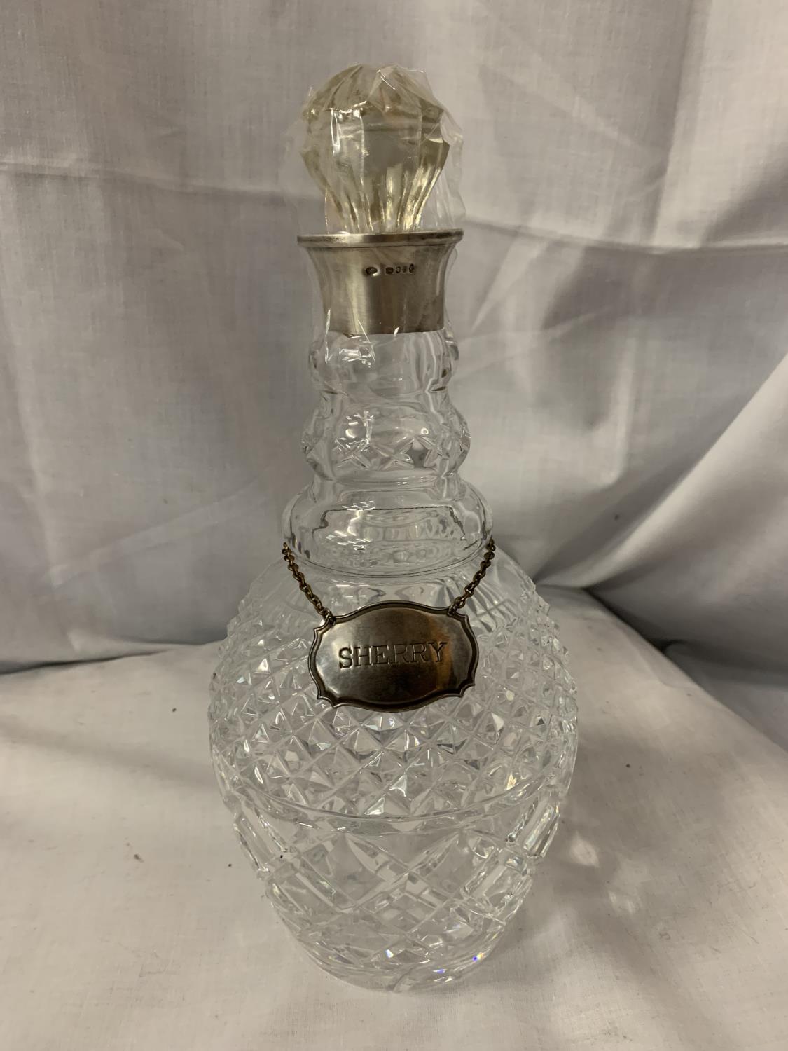 A CUT GLASS DECANTER WITH HALLMARKED COLLAR AND A WHITE METAL SHERRY LABEL