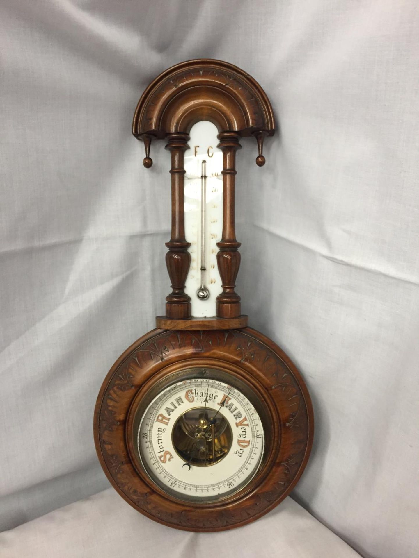 A DECORTIVE WALL BAROMETER WITH THERMOMETER A/F CRACKED GLASS ACROSS THE THERMOMETER