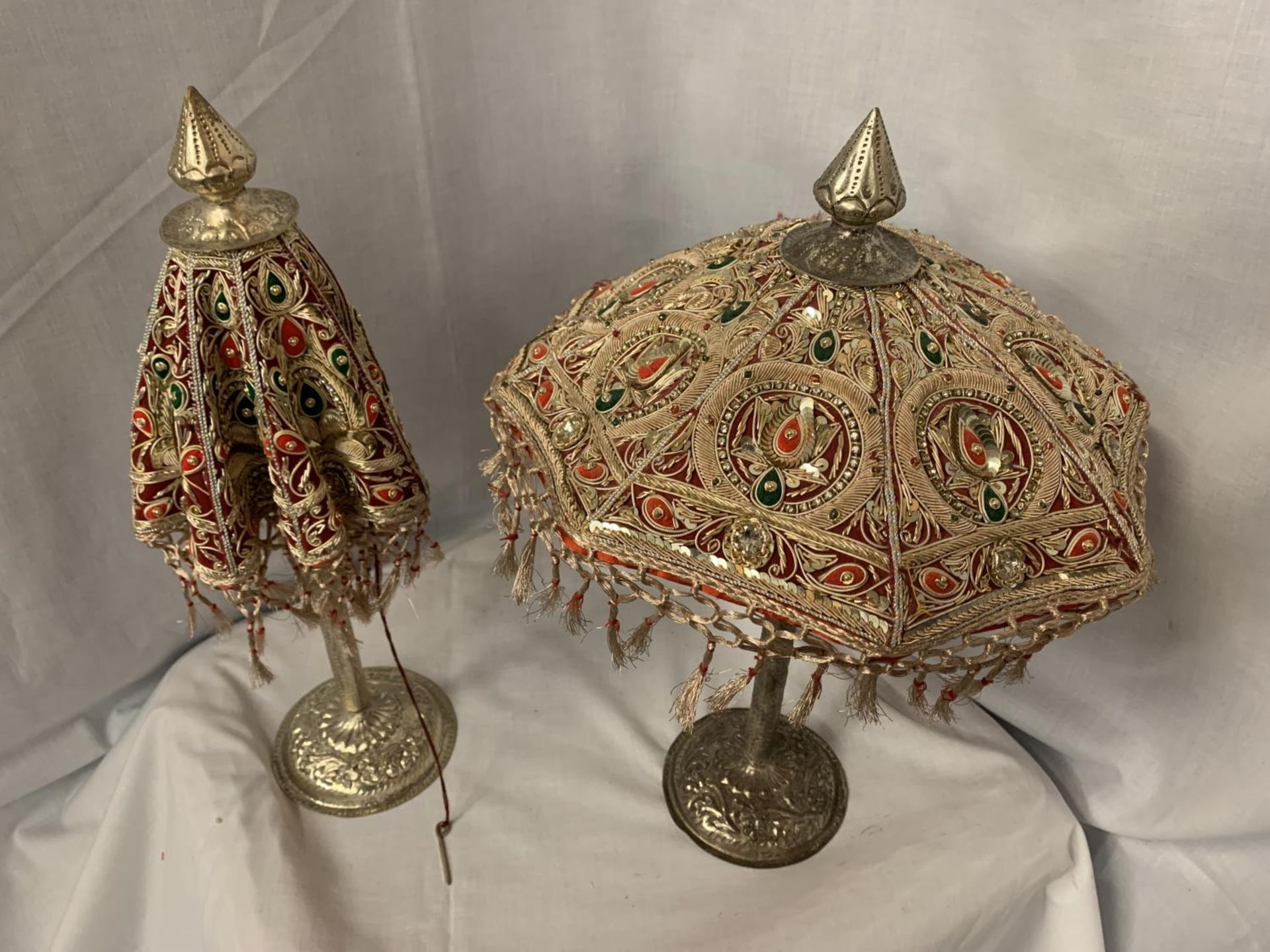 TWO METAL BASED HIGHLY DECORATIVE INDIAN ORNAMENTS IN THE STYLE OF UMBRELLAS WITH GEM, SEQUIN AND