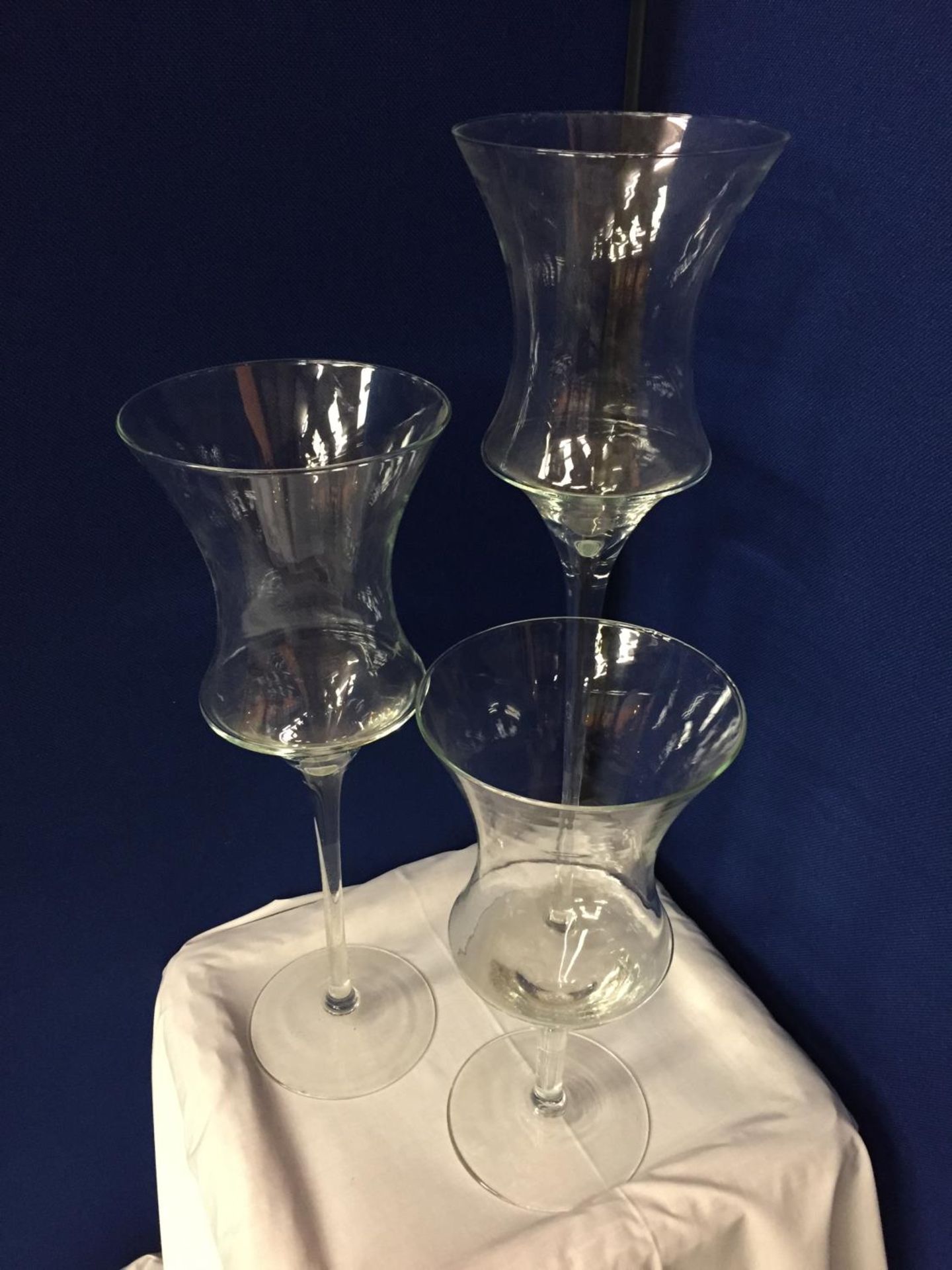THREE LARGE GLASS CANDLE HOLDERS APPROXIMATE HEIGHTS 70CM 55CM 40CM