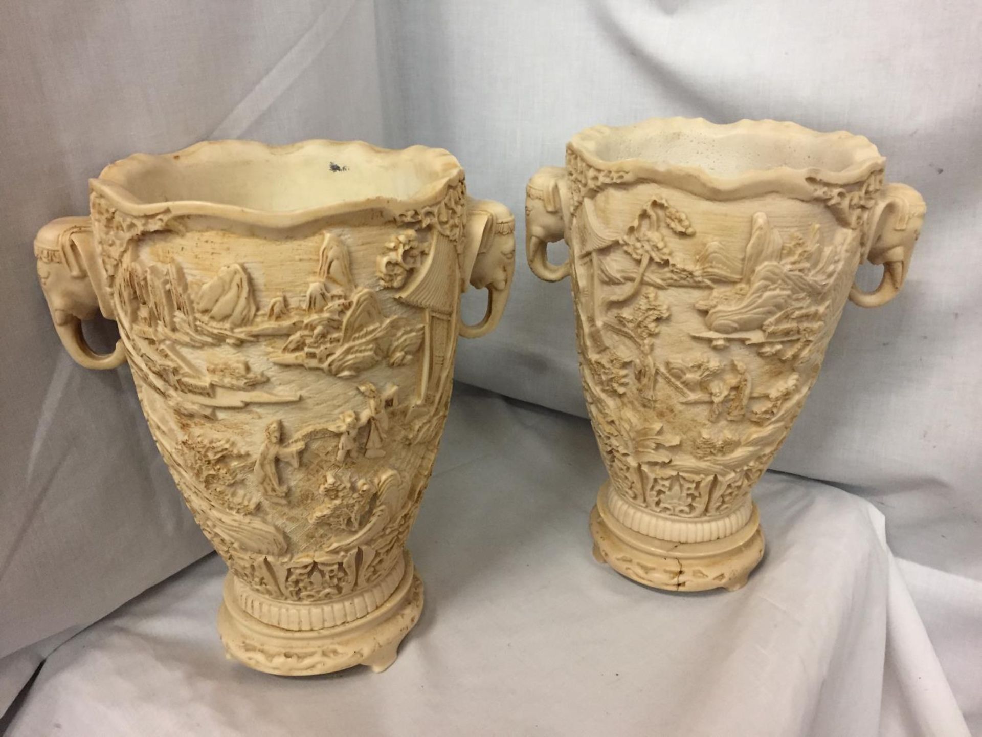 A PAIR OF HEAVILY CARVED ORIENTAL VASES WITH ELEPHANT DESIGN TWIN HANDLES 30CM HIGH